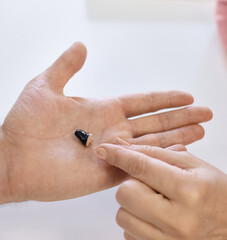 Audiologist presents a sleek hearing aid to a patient's hand for customized treatment addressing hearing loss,close-up, top view. Hearing solutions