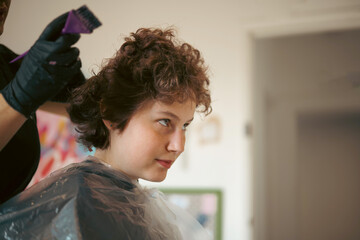 Fototapeta premium Teen age girl at salon, dyeing her hair, changing hair color