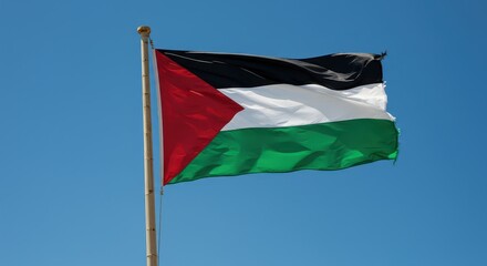 Palestinian Flag in the Wind: A vivid Palestinian flag proudly waves against a clear blue sky, its colors representing identity and cultural heritage. A symbol of resilience and hope.