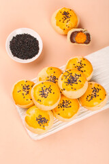 Traditional Asian Egg Yolk Pastries with Black Sesame Seeds and Sweet Bean Paste Filling on White Tray