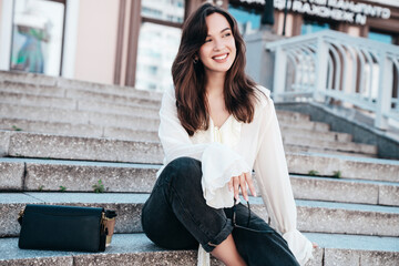Portrait of young beautiful smiling hipster woman in trendy summer white blouse and jeans. Carefree...
