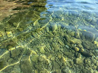 Clear sea water with underwater stones pebbles gravel sand 