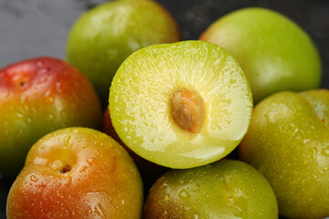 Fresh Ripe Plums Cut in Half Showing Pit and Juicy Flesh with Water Droplets