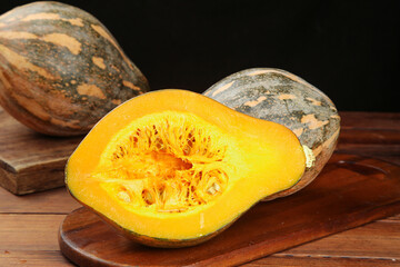 Farm-grown pumpkin and taro vegetables with vibrant orange flesh texture on wooden background