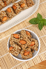 Handmade granola bars with sunflower kernels, almonds and nuts in bowl on bamboo mat - healthy organic snack food