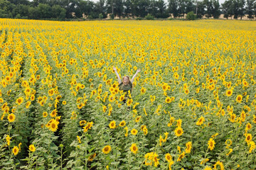a happy girl leaping in a vibrant sunflower field on a sunny summer day. Surrounded by tall sunflowers, her carefree spirit and infectious smile embody the essence of summer fun and freedom