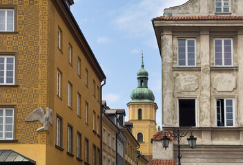 Historic buildings in Warsaw Old Town with a view of St. Martins Church tower and colorful facades.