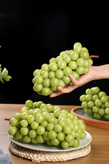 Fresh Green Grapes Elegantly Poised in Hand - Crystal-Like Fruit Display on Wooden Table