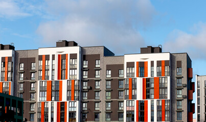 Modern residential apartment block with dark gray facade and vertical orange accents, combining