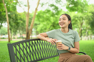 Happy female enjoying leisure time outdoors with a hot drink in hand
