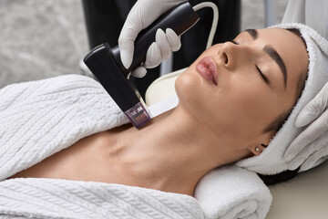Radiofrequency skin lifting of beautiful patient in beauty salon to improve elasticity and tightening of her neck skin. RF lifting
