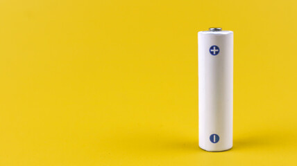 White metal AA-size battery isolated on yellow background.