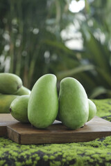 Fresh Raw Green Mangoes on Wooden Board in Tropical Garden Setting