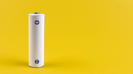 White metal AA-size battery isolated on yellow background.