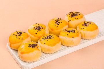 Handmade egg yolk pastries with sesame seeds on wooden serving board