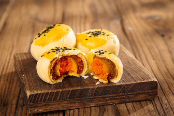Asian Egg Custard Pastries with Golden Yolk Centers on Wooden Board - Traditional Handmade Dessert Snacks
