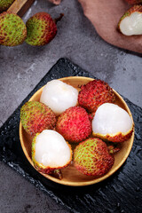 Fresh Hainan Lychee Fruits in Wooden Bowl on Black Slate - Tropical Asian Exotic Fruit with White Flesh