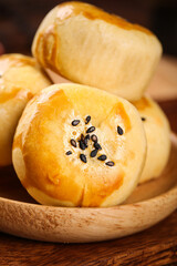 Golden Handmade Bread Rolls with Sesame Seeds in Wooden Bowl on Rustic Table