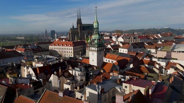Aerial drone shot approaching the iconic white clocktower of the Old Town Hall (Stara radnice) in Brno, Czechia, showcasing the historic South Moravian city center on a clear spring day.