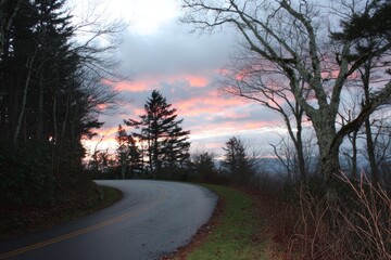Obraz premium Winding mountain road at sunset, colorful clouds