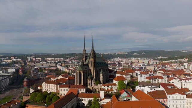 Aerial drone pan out shot revealing the majestic Cathedral of St. Peter and Paul Gothic spires dominating the historic Brno skyline, Czechia.