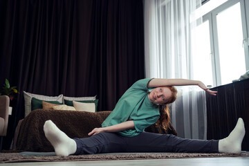 Young woman stretching at home during a morning workout in cozy living room