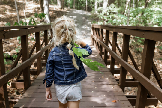 Child crossing wooden bridge on hiking trail