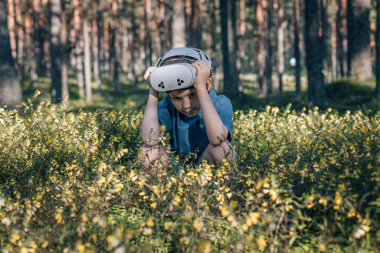 Child in virtual glasses sits in flowers