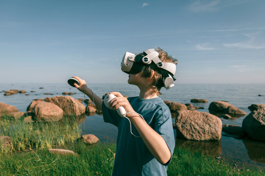 Child in virtual glasses with joysticks plays