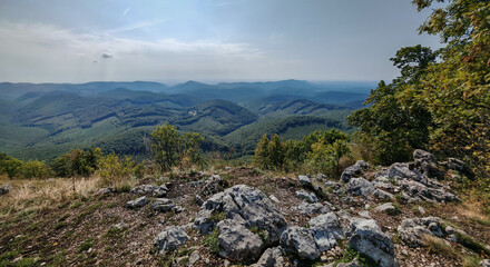Expansive panorama from a hidden rocky outcrop near H&aacute;rom-kő in the B&uuml;kk Mountains, Hungary, with forested ridges fading into the horizon.