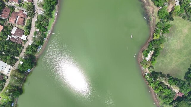 Aerial view showcases a serene lake bordered by lush greenery and quaint village homes creating a
