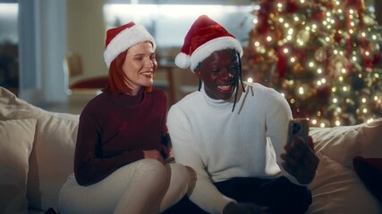 Merry Christmas holidays, biracial loving couple calling by video in smartphone. Happy multiethnic people celebrating winter fest at home and chatting with friends and family online, portrait in room