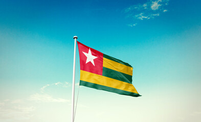 Togo flag waving in blue sky with mast.