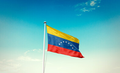 Venezuela flag waving in blue sky with mast.