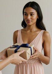 Young asian female receives gift wrapped in brown paper with navy ribbon