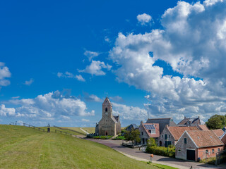 Fototapeta premium Village view with the Mariakerk with the Wadden Sea dike in Wierum, Friesland province, The Netherlands