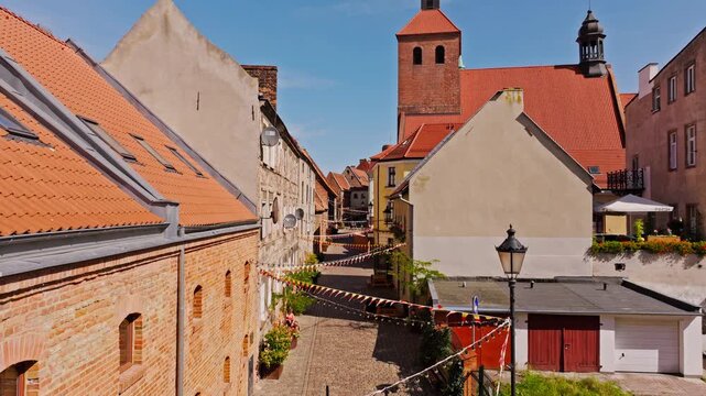 Drone glides forward through Grudziadz alley lined with bricks and flowers