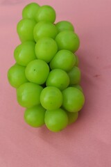 Fresh Shine Muscat or Vitis grapes close up, isolated on pink background.