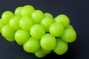 Fresh Shine Muscat or Vitis grapes close up, isolated on dark background.