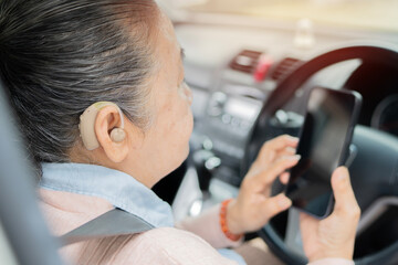 Asian grandmother woman with hearing aid holding mobile phone