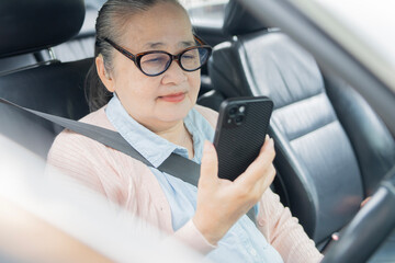 Smiling senior woman holding smart phone while sitting in car