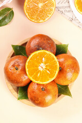 Fresh Orange Display in Wooden Bowl with Green Leaves and Sliced Citrus Fruit