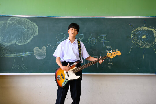 教室でベースギターを演奏する男子学生　音楽・青春・学校生活イメージ