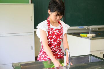 料理教室で調理を学ぶ小学生の女の子と料理の先生　教育と食育イメージ