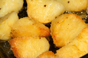 Close up of delicious fresh roast potatoes cooking in fat oil close up