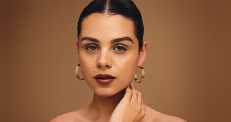 Portrait, earrings and woman with makeup in studio for aesthetic, glow or brown background. Beauty,...