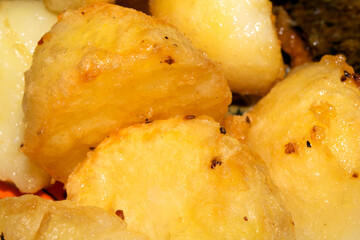 Close up of delicious fresh roast potatoes cooking in fat oil close up