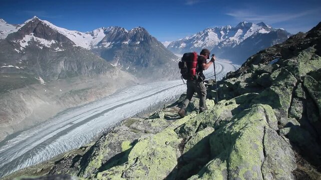 Hiker hiking above the Aletsch glacier in the Swiss Alps, view up glacier