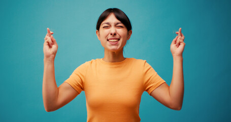 Emotional Hispanic woman makes wish looking upward on blue
