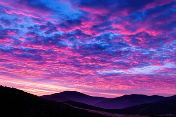 Vibrant sunrise paints the sky with pink and blue hues over silhouetted mountains